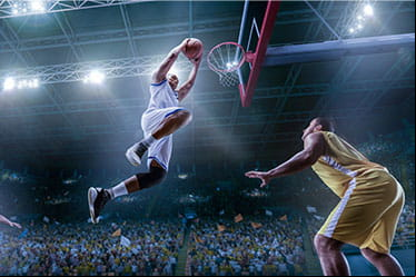 A male basketball player dunking over his opponent.