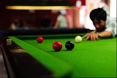 A male snooker player lines up his shot.